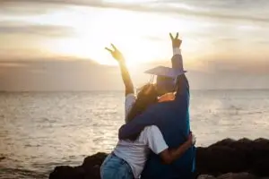 Graduates celebrating by the sea, symbolizing the success and bright future fostered by well-lit educational environments