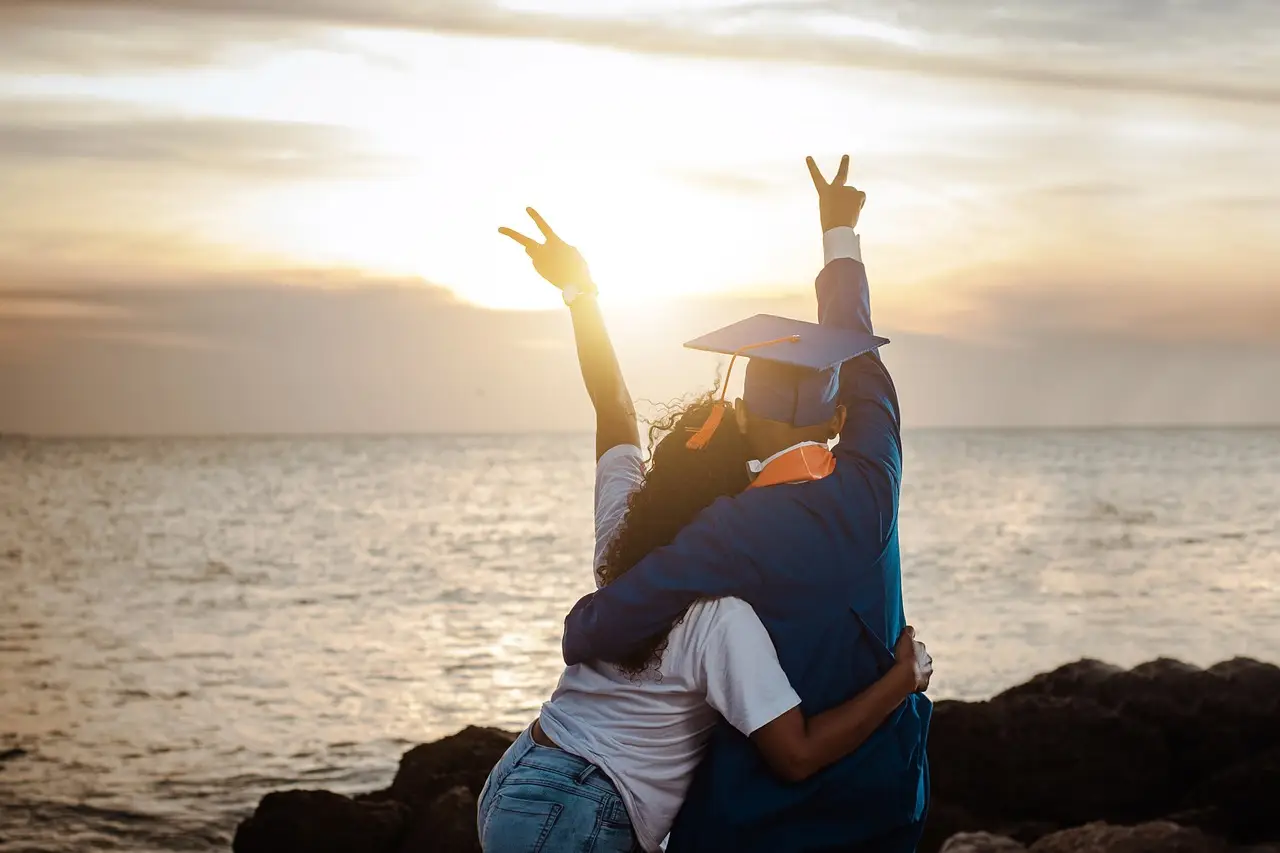 Graduates celebrating by the sea, symbolizing the success and bright future fostered by well-lit educational environments